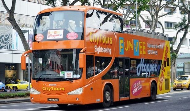Lively orange FunVee Hop-on Hop-off bus, energizing the streets of Singapore with its vibrant presence and exciting city exploration.